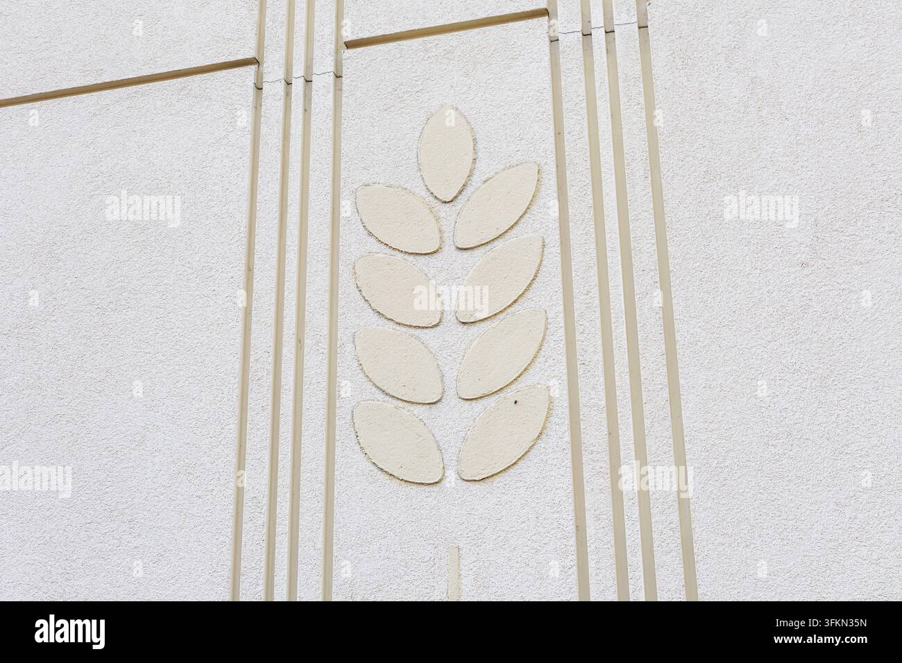 Dekoratives Weizenähren-Relief an weißer strukturierter Gebäudewand Stockfoto