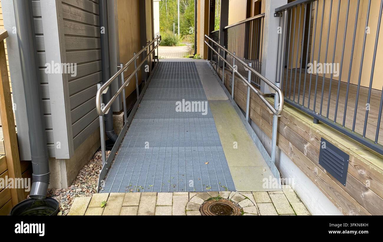 Zugängliche Rollstuhlrampe mit Metallgeländern am Eingang eines Wohngebäudes Stockfoto