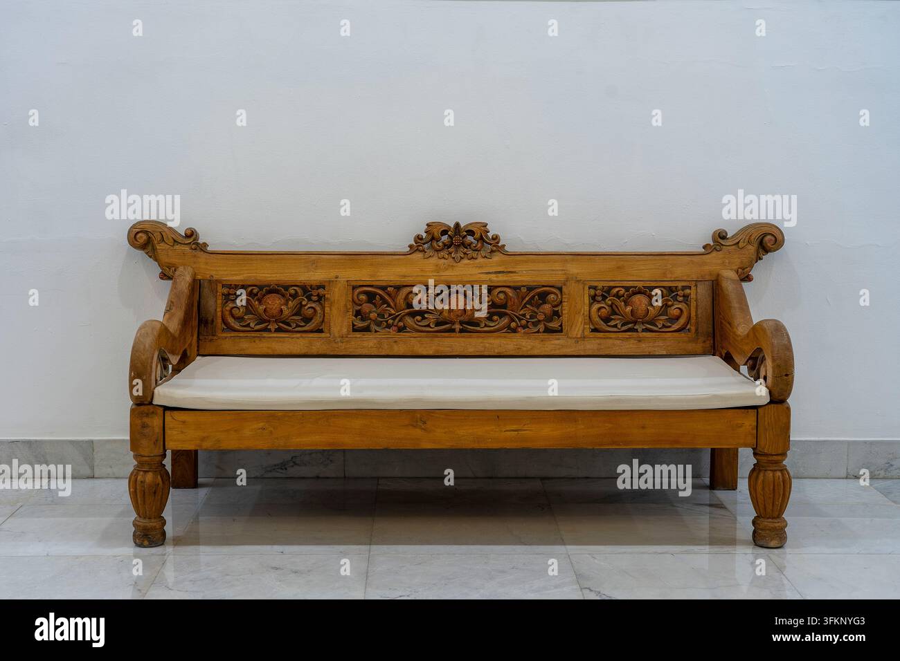 Holzsofa mit Kissen in der Nähe einer weißen Betonwand in einem leeren Wohnzimmer-Interieur, Ägypten Stockfoto