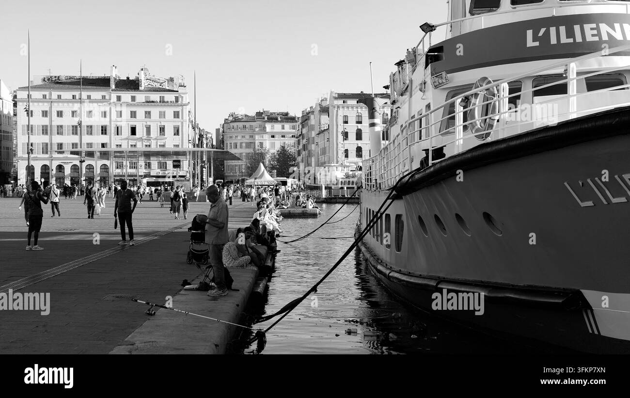 MARSEILLE, FRANKREICH - 16. SEPTEMBER 2026 - Die ILENNE-Fähre liegt im Vieux Port vor Anker, während Menschen auf der Promenade spazieren gehen und angeln Stockfoto