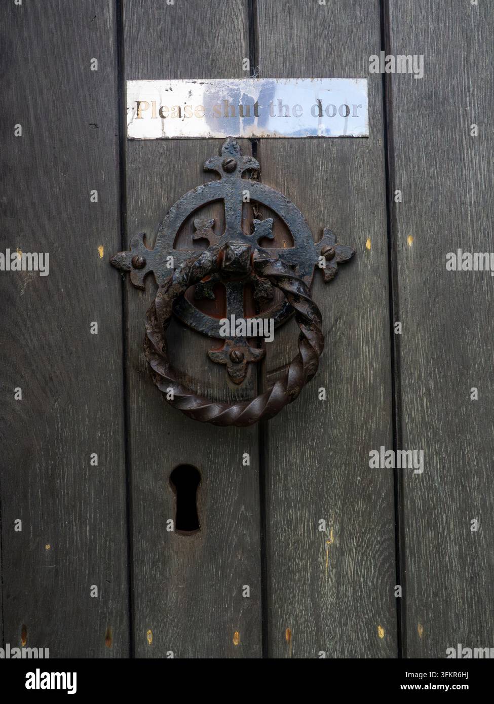 20. September 2026, Loweswater, Vereinigtes Königreich. Ein verwitterter, verzierter Metallklopfer und ein verblasstes Schild mit der Bitte an Besucher: "Bitte schließen Sie die Tür" Stockfoto