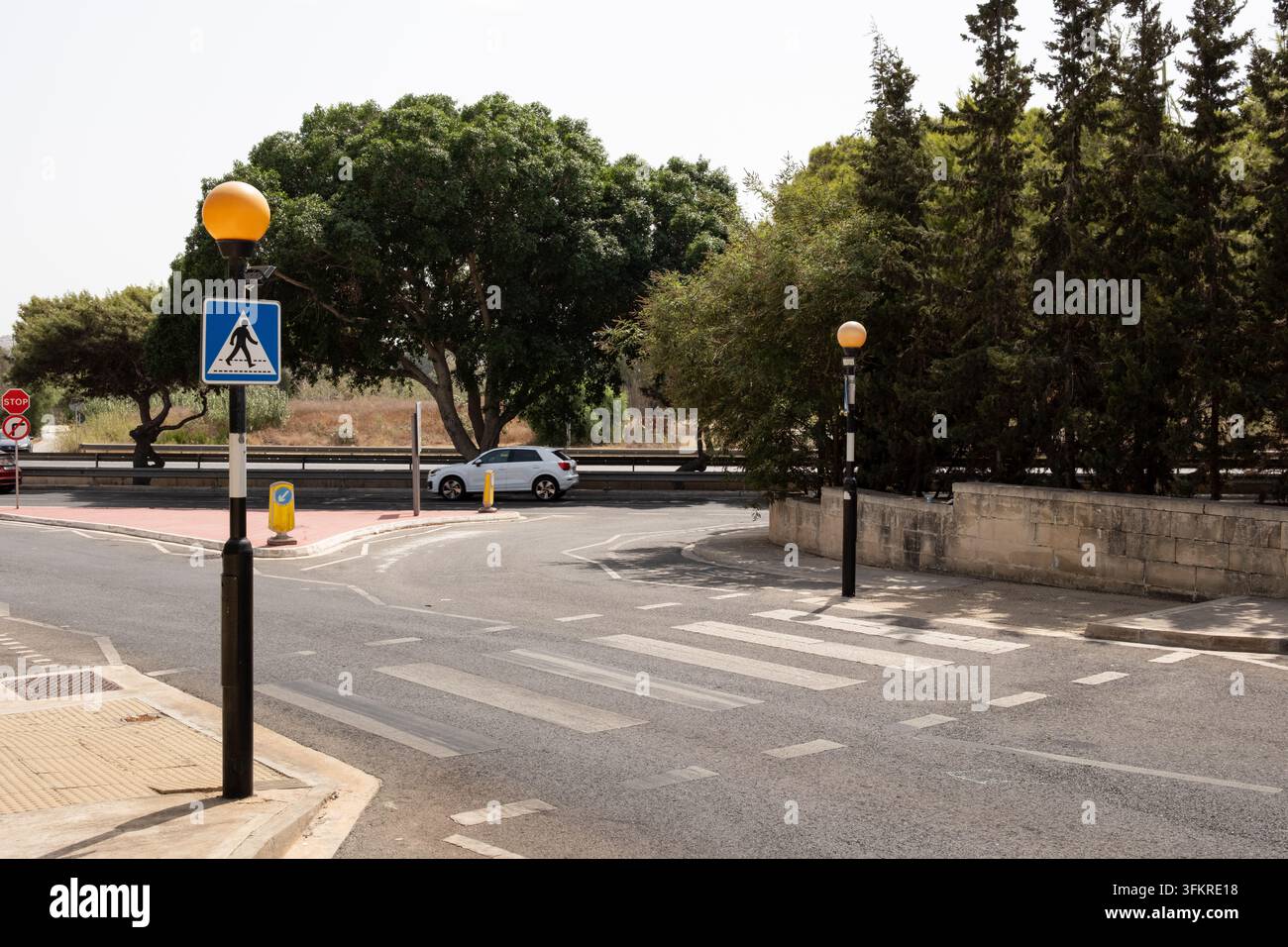 Ein leerer Fußgängerpelikanüberweg mit Zebrastreifen und blauem quadratischem Weißdreieck mit Grafikschild eines überquerenden Mannes Stockfoto