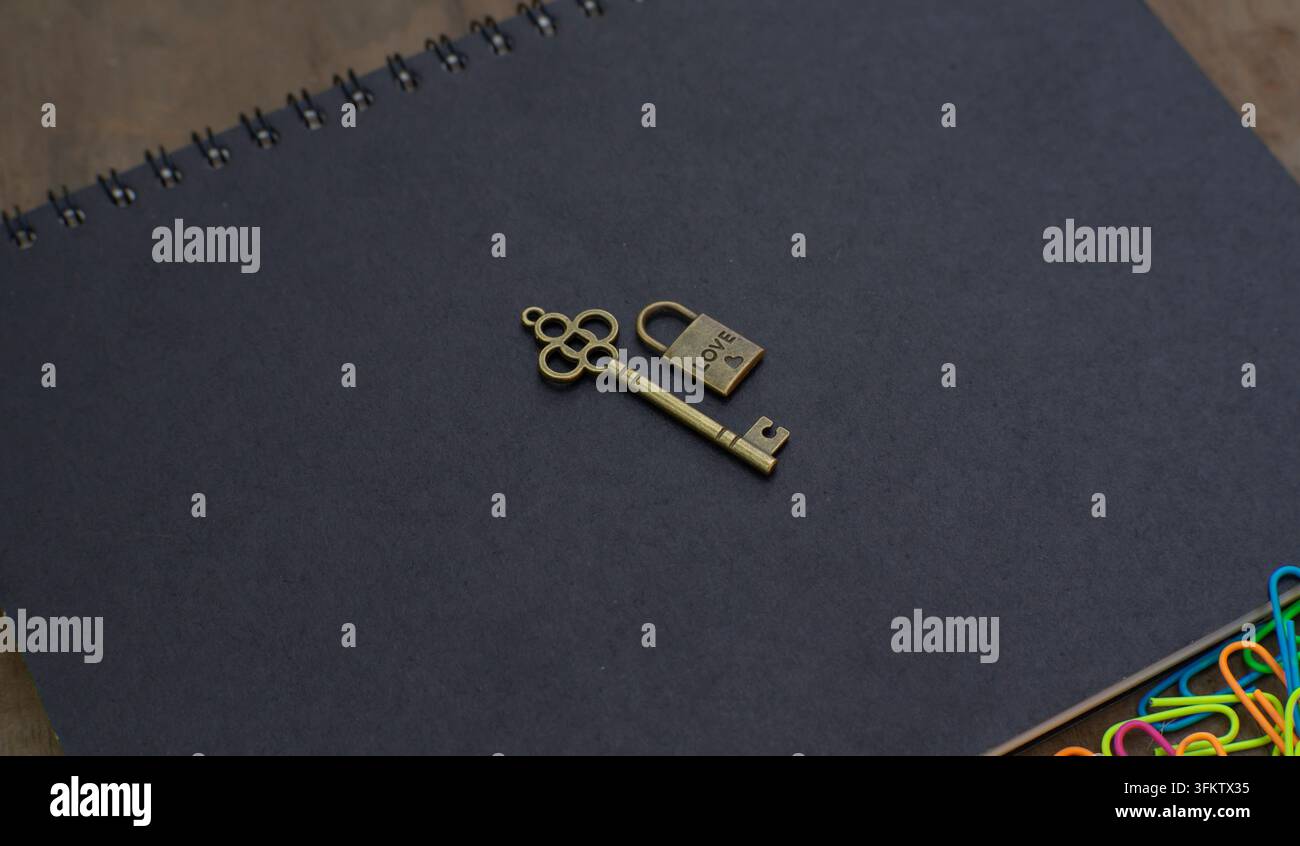 Liebesverschluss und Herzschlüssel neben einem Notizbuch, der Romantik, Hingabe, Vertrauen und dauerhafte Beziehungs Konzepte repräsentiert. Stockfoto