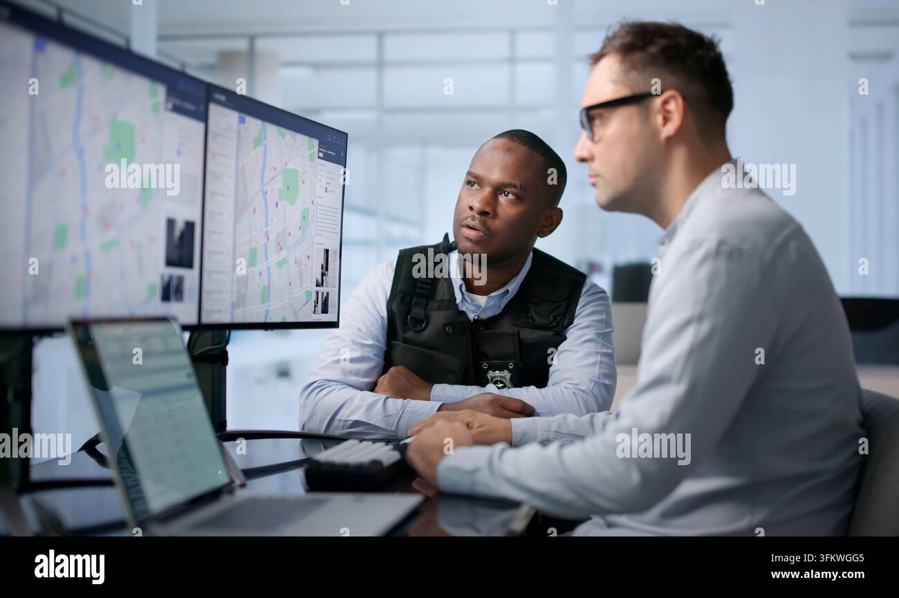 Polizeianalyst überprüft Kriminalitätsdaten auf einem Laptop mit fortschrittlicher georäumlicher Kartensoftware. Stockfoto