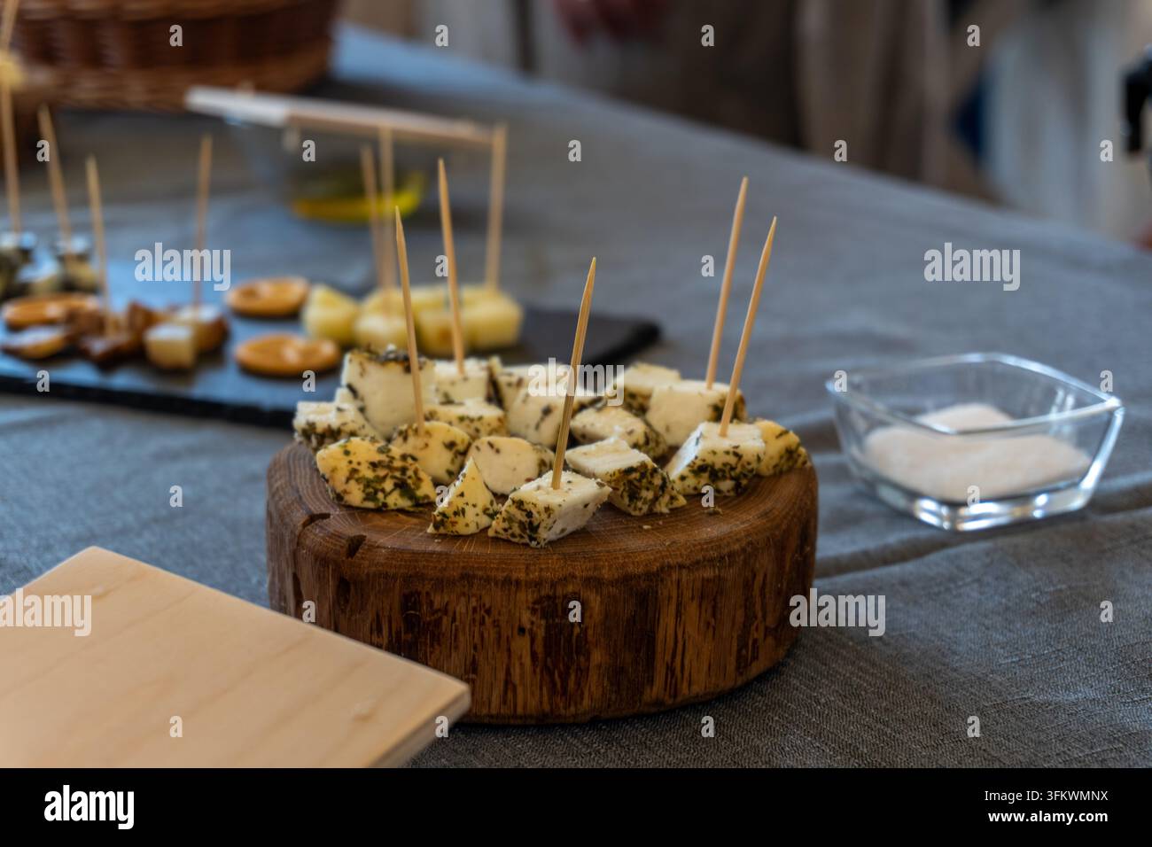 Mit Kräutern überzogene Käuwürfel mit Spießen auf einem Holzbrett Stockfoto