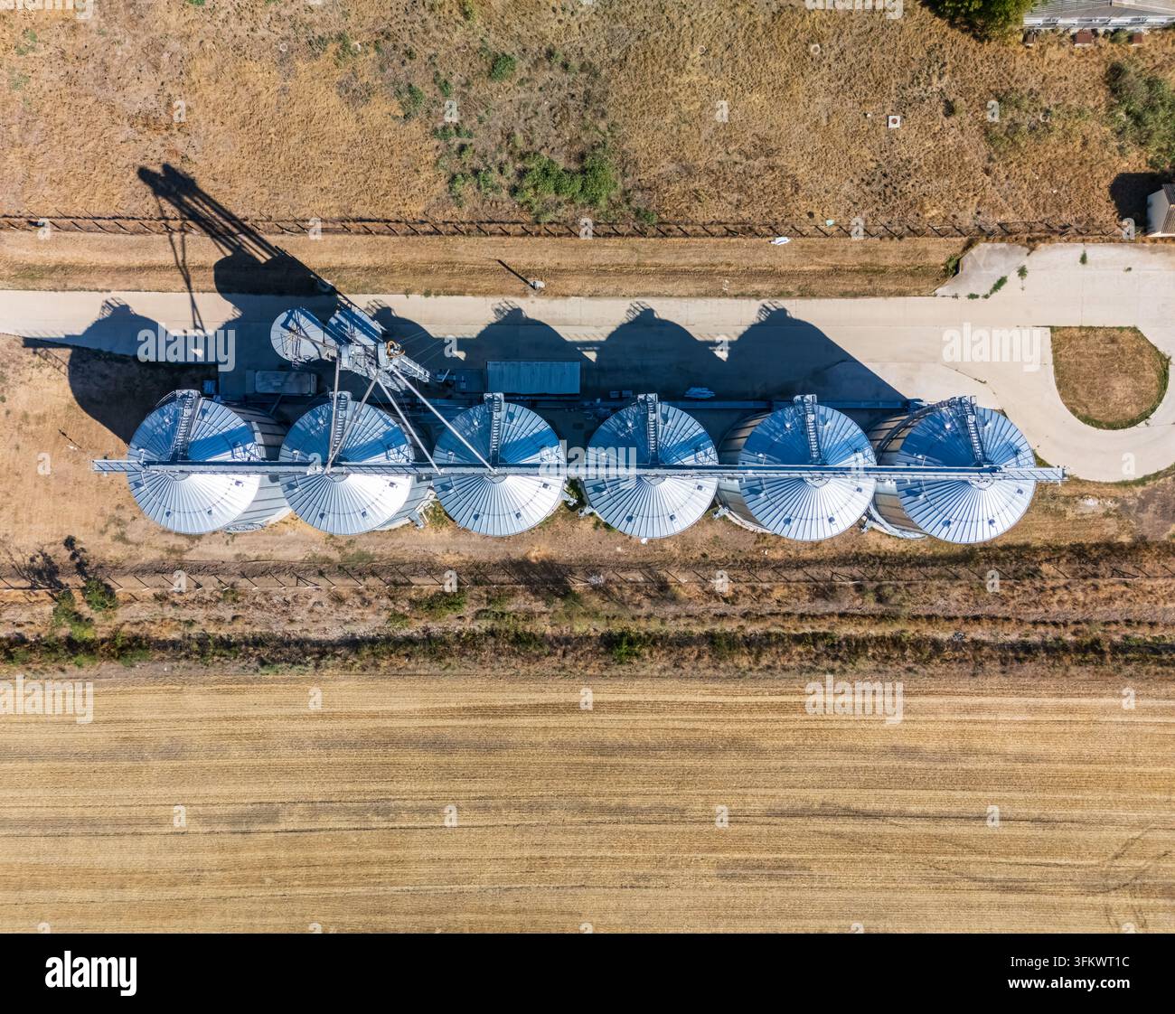 Luftaufnahme von Getreidesilos und Metalllagertanks an einer landwirtschaftlichen Anlage in Paszto, Nograd County, Ungarn, umgeben von Sommerfeldern und Ruinen Stockfoto
