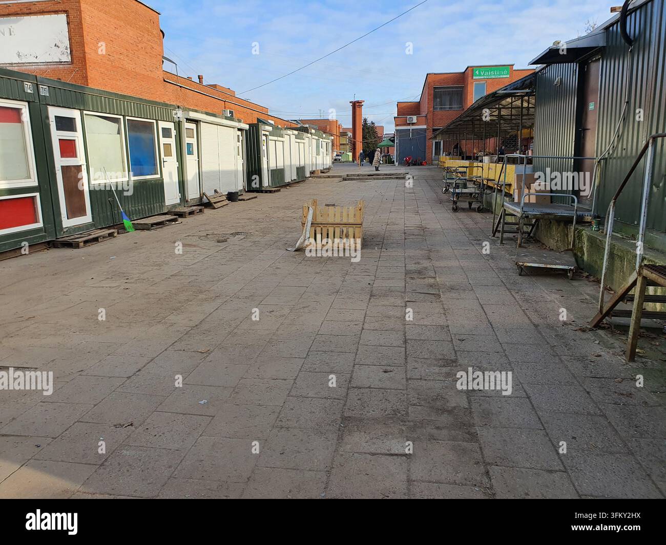 Ein Außenmarktbereich mit temporären Containerkonstruktionen und Marktständen. Die Szene zeigt einen breiten gepflasterten Gehweg mit mobilen Kabinen in Grün, Stockfoto