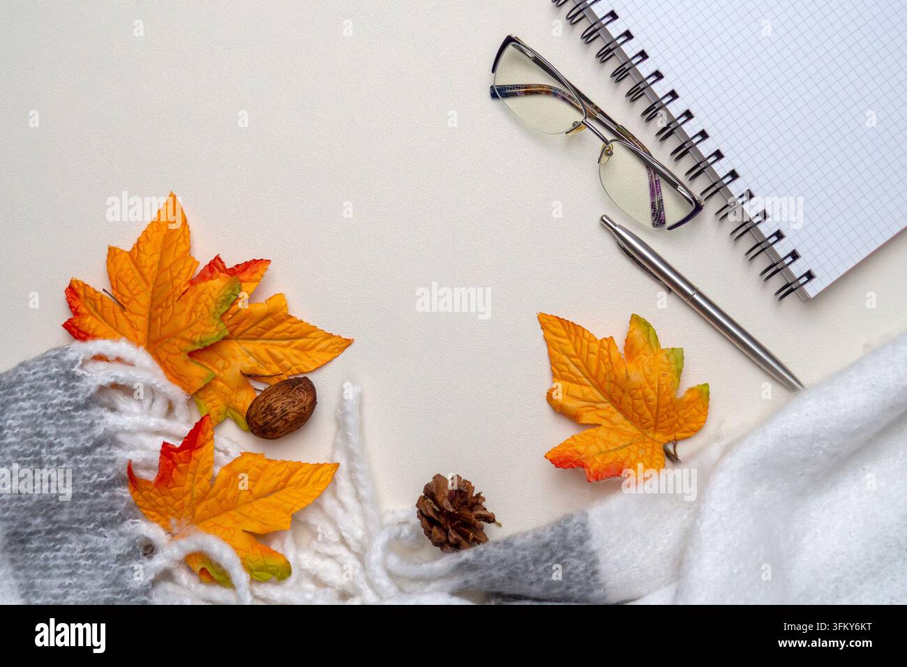 Herbstliche Stillleben mit Blättern, Schal und Schreibwerkzeugen für gemütliches, kreatives Stockfoto