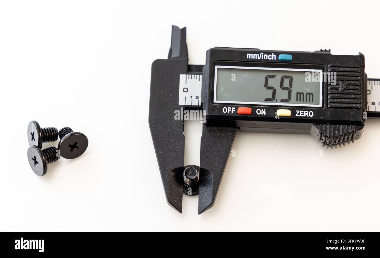 Eine digitale Bremssattel misst eine kleine schwarze Schraube auf weißem Hintergrund Stockfoto