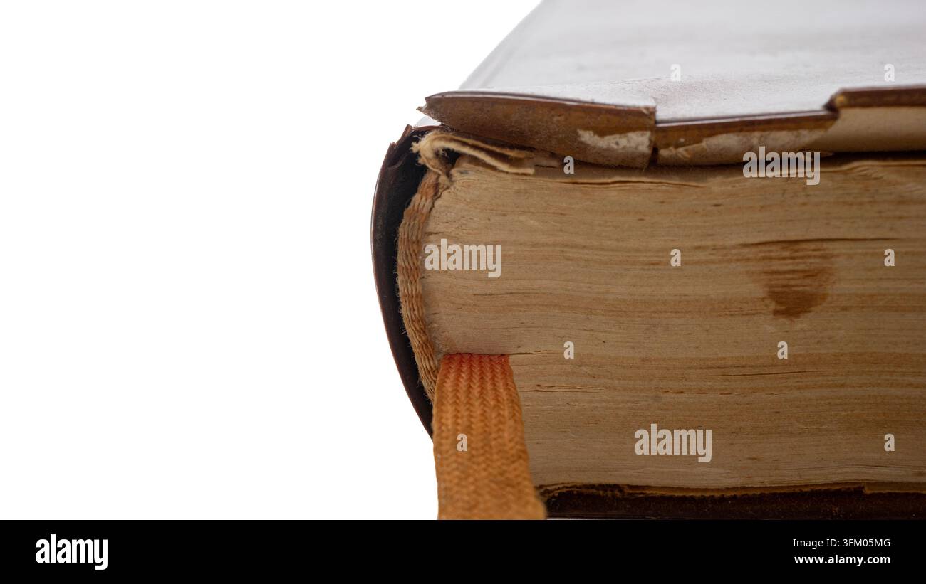 Diese Nahaufnahme zeigt ein altes Buch, das auf einer flachen Oberfläche ruht. Das Buch hat abgenutzte Kanten und einen sichtbaren Leseband, der herausragt. Stockfoto