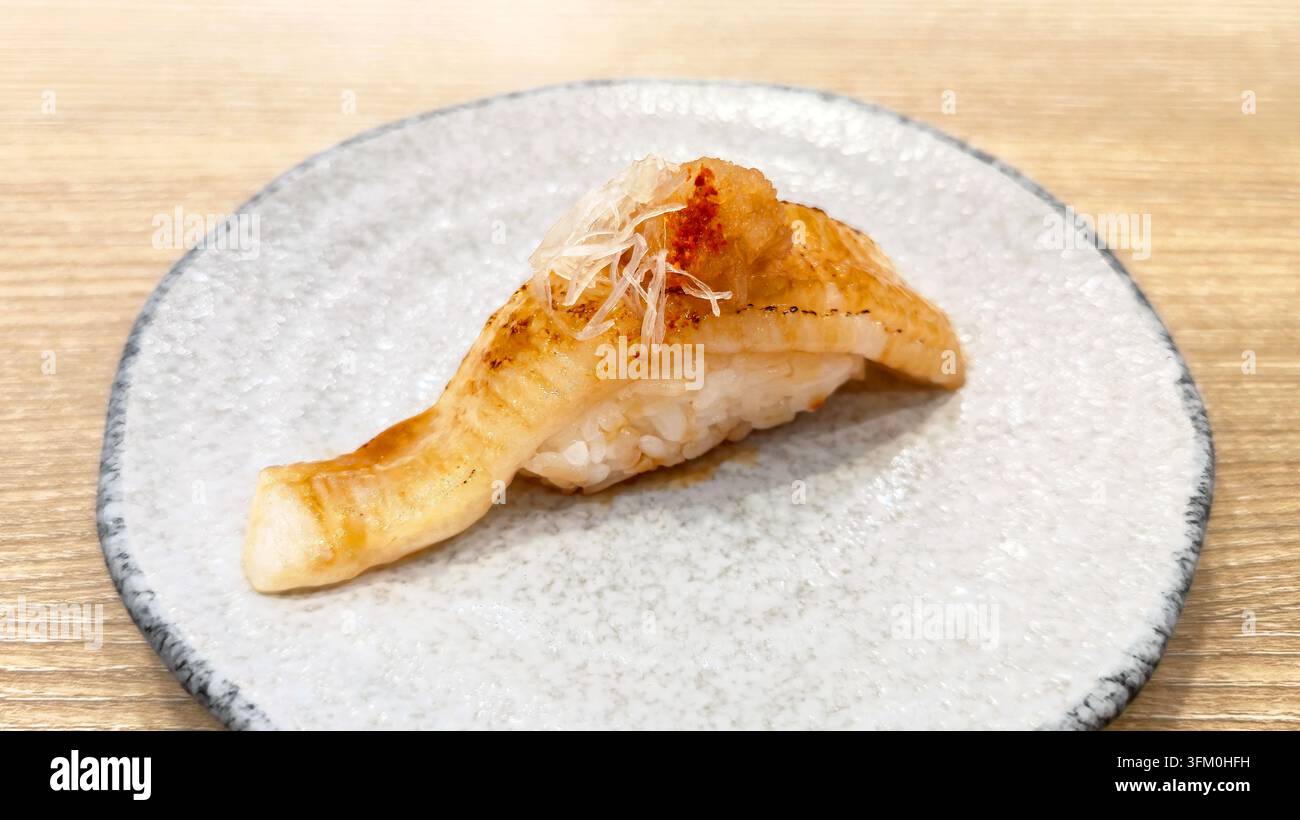 Aburi Nigiri Sushi mit gegrilltem Fisch und geriebenem Rettich, serviert auf einem Keramikteller in einem japanischen Restaurant. - Smartphone-aufgenommenes Stockfoto
