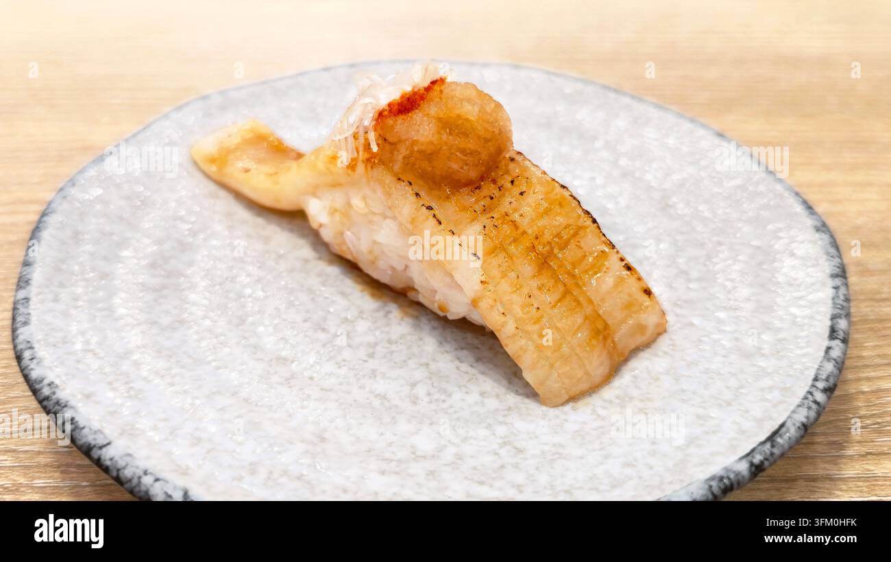 Aburi Nigiri Sushi mit gegrilltem Fisch und geriebenem Rettich, serviert auf einem Keramikteller in einem japanischen Restaurant. - Smartphone-aufgenommenes Stockfoto