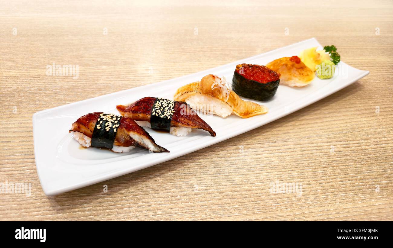 Verschiedenes japanisches Nigiri-Sushi-Set mit gegrilltem Aal, gebratenem Lachs, Lachs-Rogen und Meeresfrüchten, serviert mit Wasabi und Ingwer in einer weißen Schale. - Smartphone-aufgenommenes Stockfoto