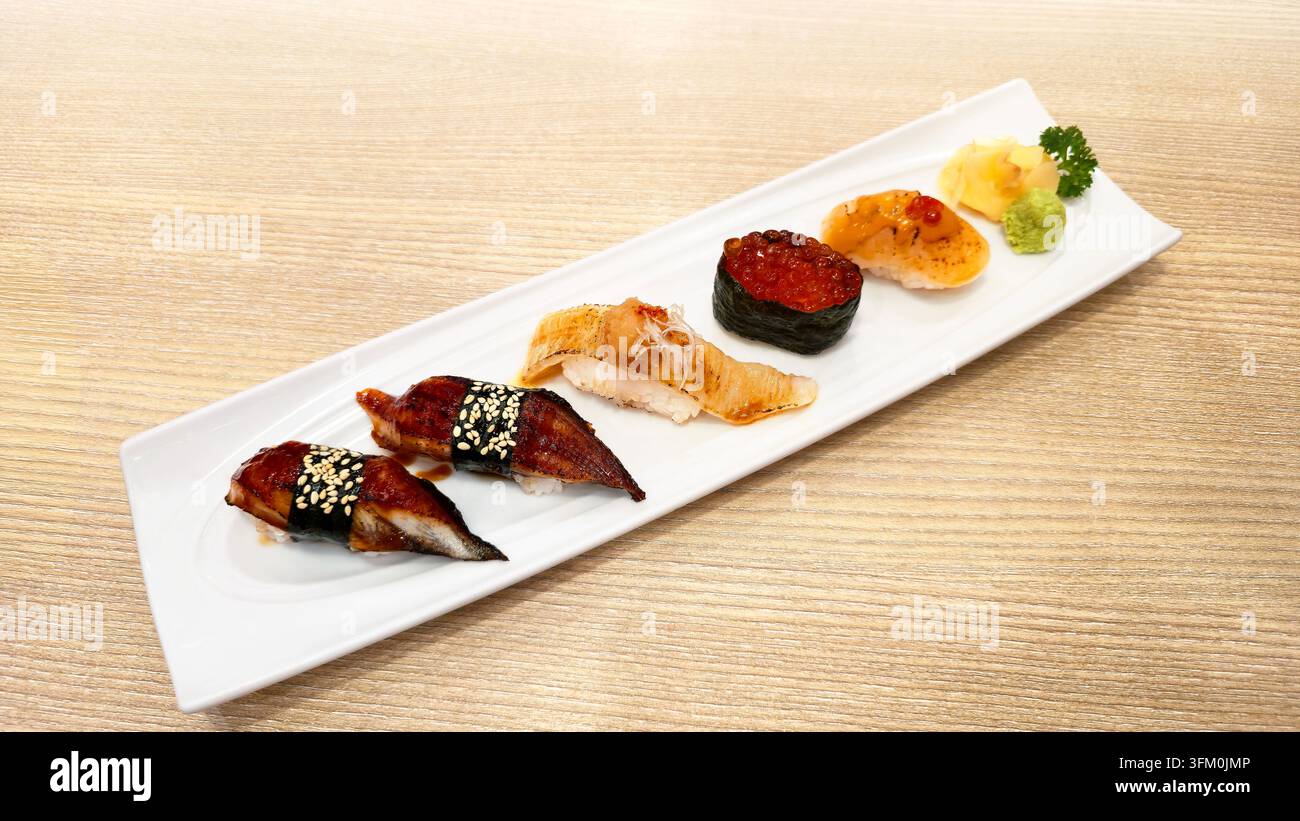 Verschiedenes japanisches Nigiri-Sushi-Set mit gegrilltem Aal, gebratenem Lachs, Lachs-Rogen und Meeresfrüchten, serviert mit Wasabi und Ingwer in einer weißen Schale. - Smartphone-aufgenommenes Stockfoto