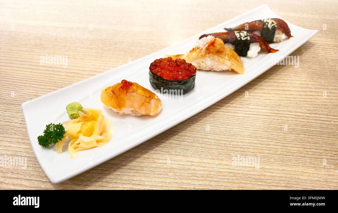 Verschiedenes japanisches Nigiri-Sushi-Set mit gegrilltem Aal, gebratenem Lachs, Lachs-Rogen und Meeresfrüchten, serviert mit Wasabi und Ingwer in einer weißen Schale. - Smartphone-aufgenommenes Stockfoto