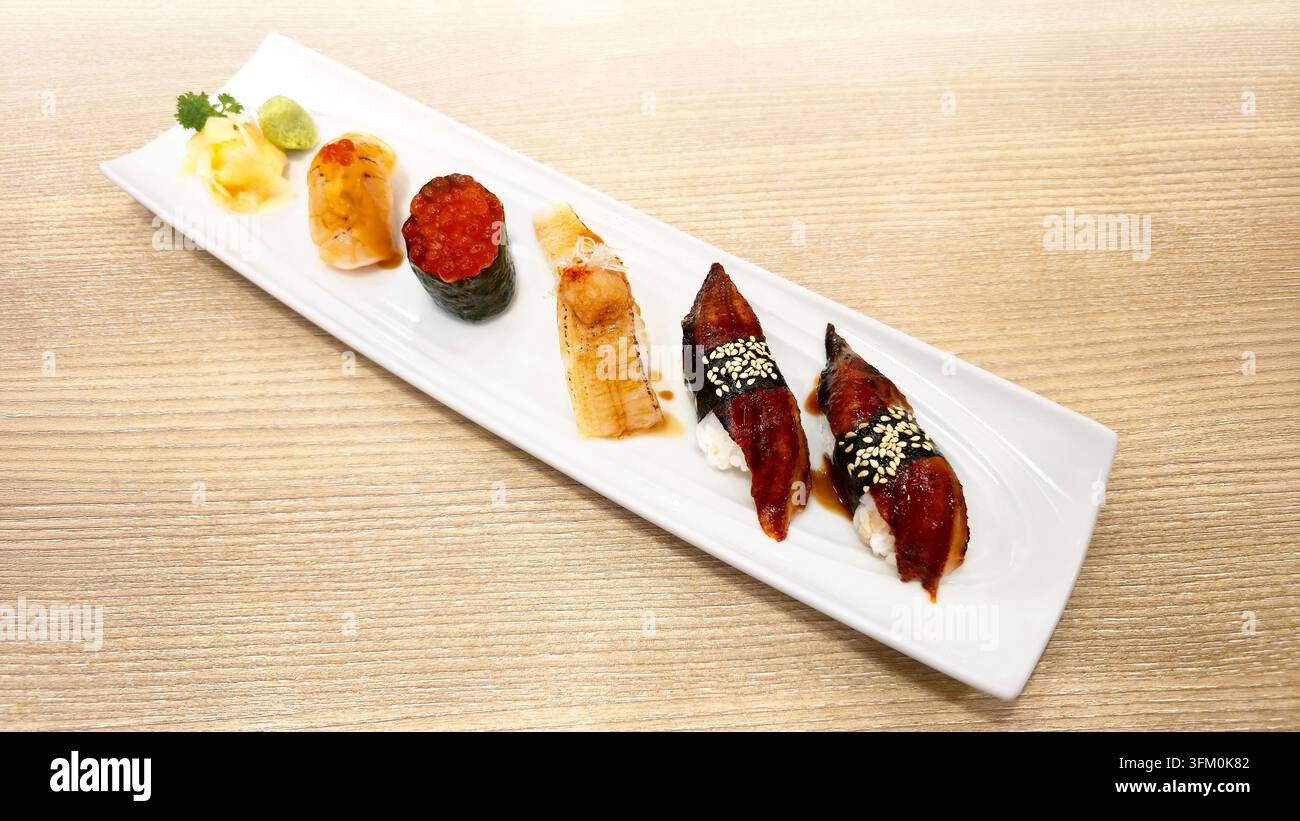 Verschiedenes japanisches Nigiri-Sushi-Set mit gegrilltem Aal, gebratenem Lachs, Lachs-Rogen und Meeresfrüchten, serviert mit Wasabi und Ingwer in einer weißen Schale. - Smartphone-aufgenommenes Stockfoto