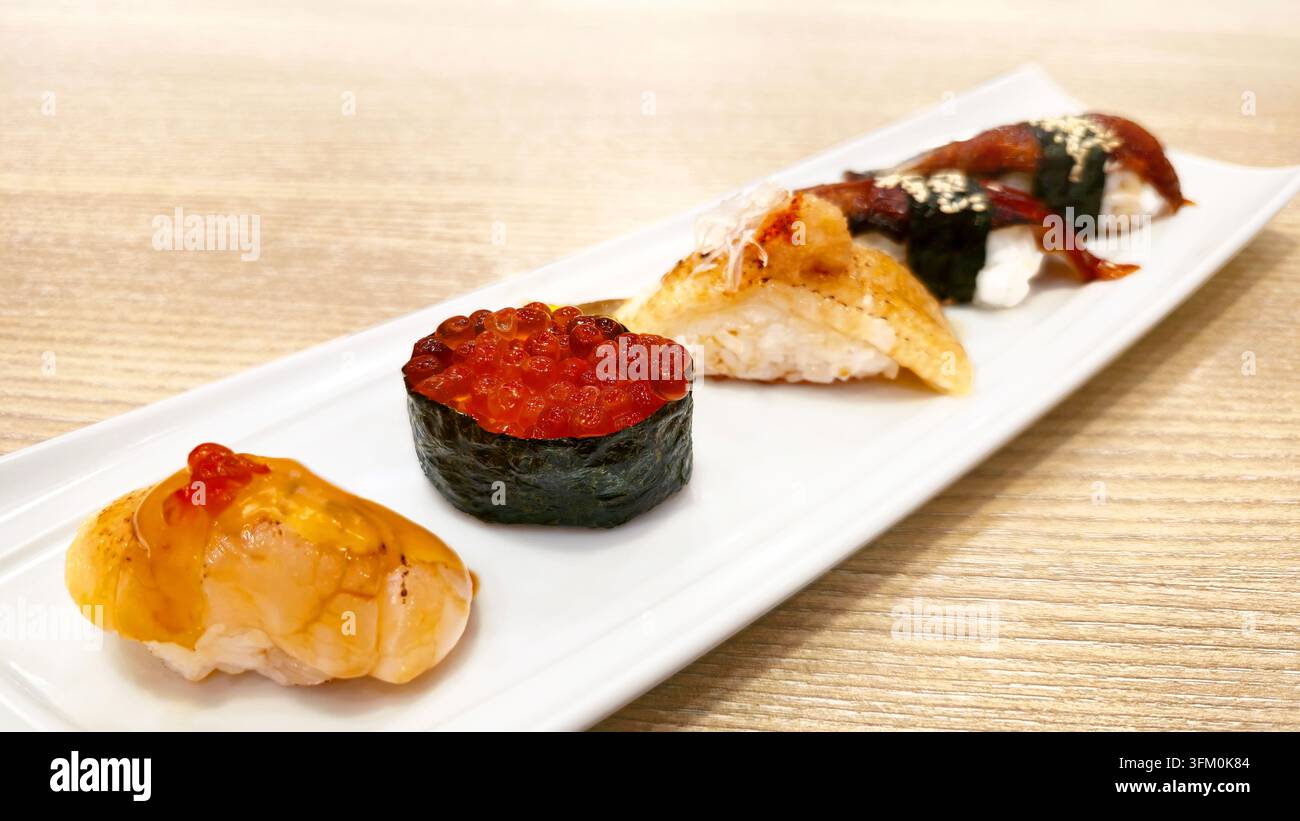 Verschiedenes japanisches Nigiri-Sushi-Set mit gegrilltem Aal, gebratenem Lachs, Lachs-Rogen und Meeresfrüchten, serviert mit Wasabi und Ingwer in einer weißen Schale. - Smartphone-aufgenommenes Stockfoto