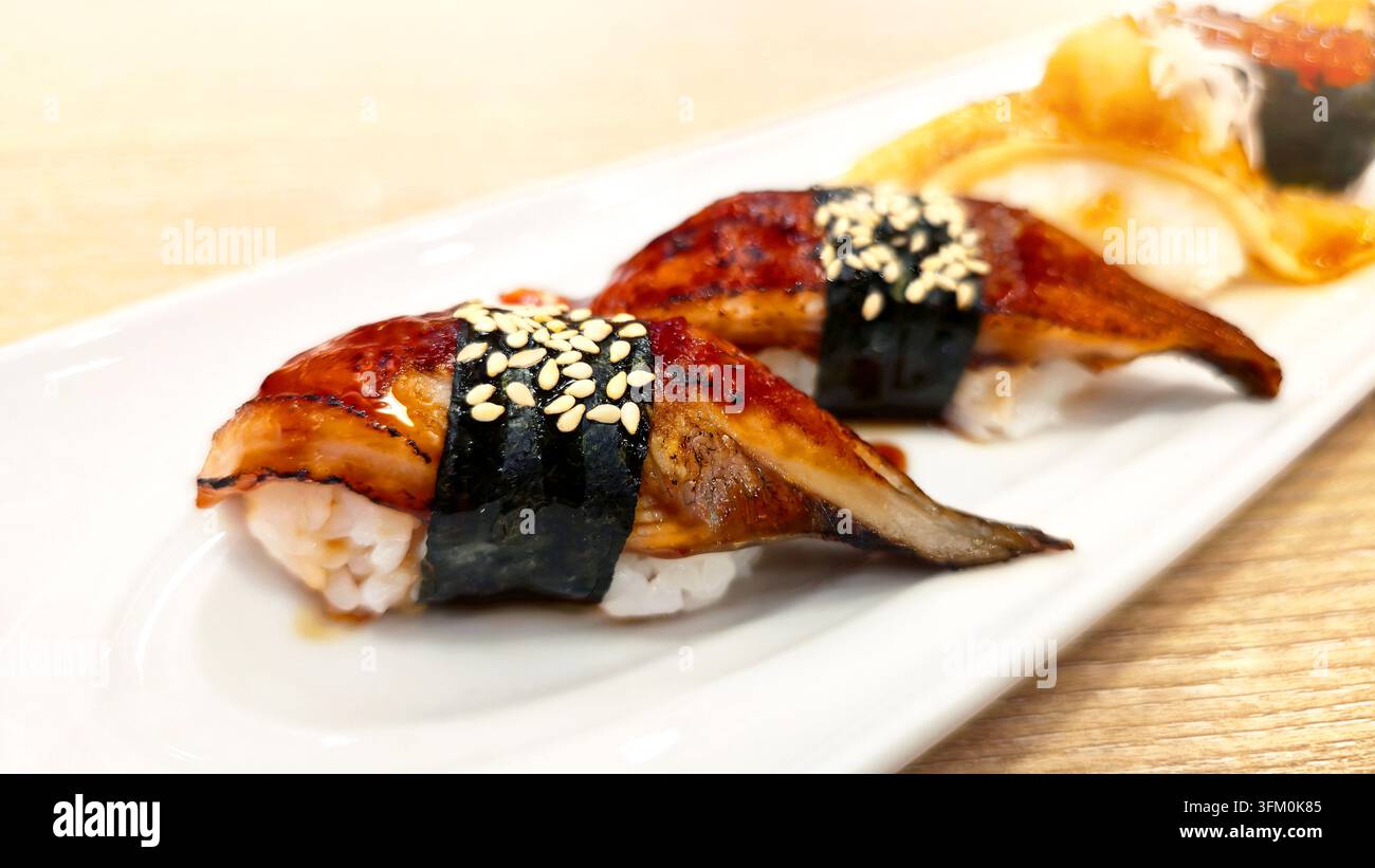 Verschiedenes japanisches Nigiri-Sushi-Set mit gegrilltem Aal, gebratenem Lachs, Lachs-Rogen und Meeresfrüchten, serviert mit Wasabi und Ingwer in einer weißen Schale. - Smartphone-aufgenommenes Stockfoto