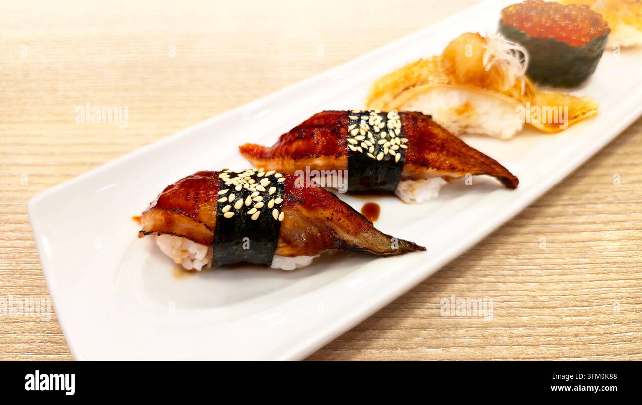 Verschiedenes japanisches Nigiri-Sushi-Set mit gegrilltem Aal, gebratenem Lachs, Lachs-Rogen und Meeresfrüchten, serviert mit Wasabi und Ingwer in einer weißen Schale. - Smartphone-aufgenommenes Stockfoto