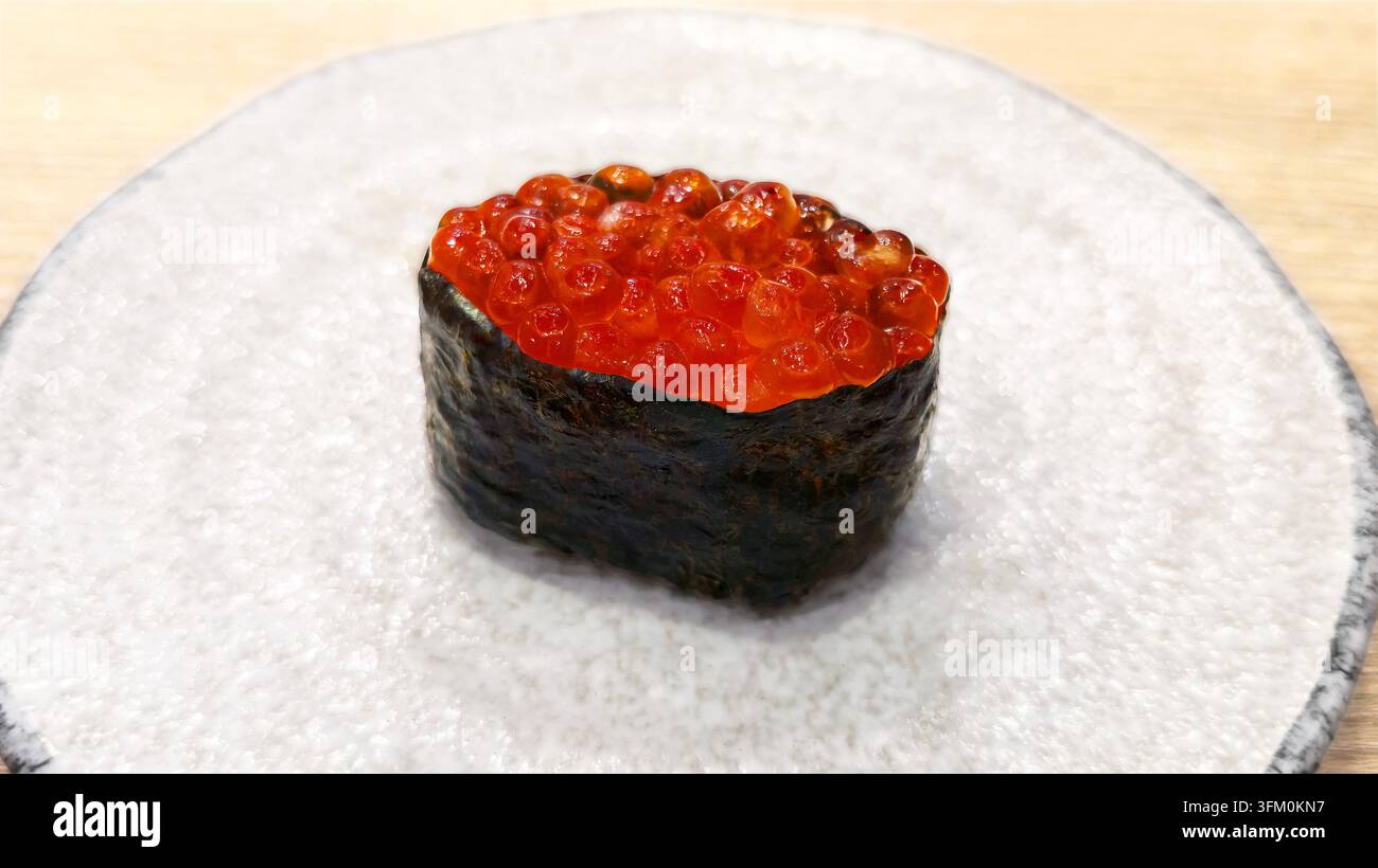 Japanisches Ikura-Gunkan-Sushi mit leuchtender Lachs-Rohkape, in knusprigem Nori-Algenblätter eingerollt, einzeln auf einem Keramikteller serviert - Smartphone-aufgenommenes Stockfoto