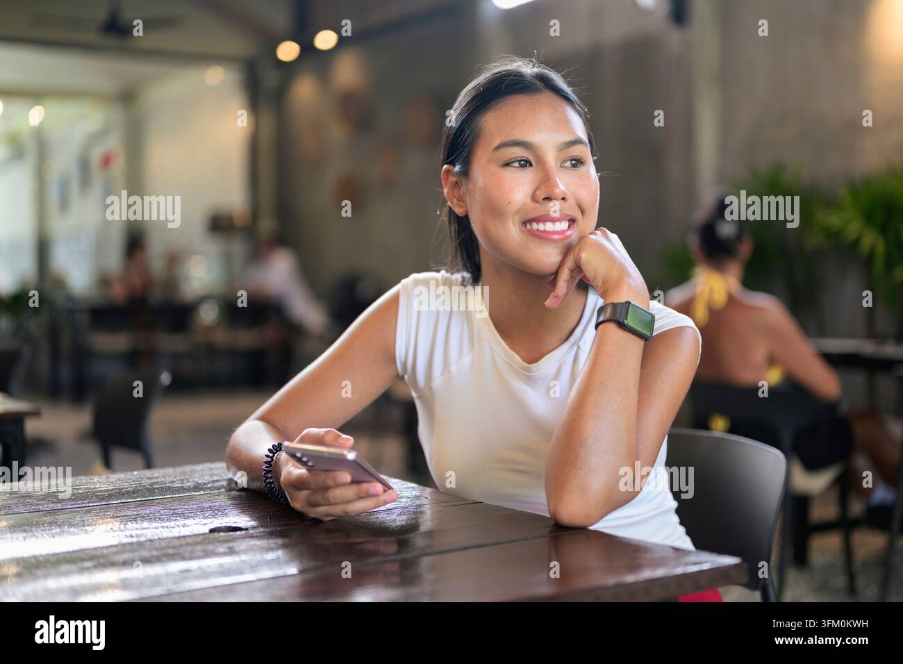 Glückliche Frau, die sich im Café entspannt, während sie ihr Handy hält Stockfoto