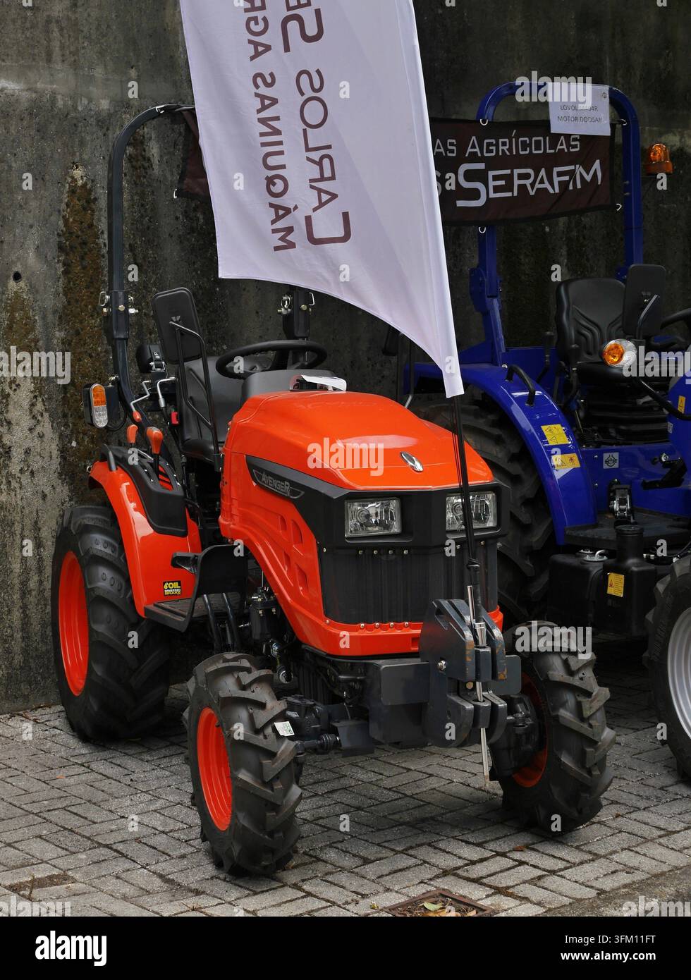 Neuer orangefarbener kompakter Nutztraktor mit weißer Fahne und Banner mit Serafim-Branding Stockfoto