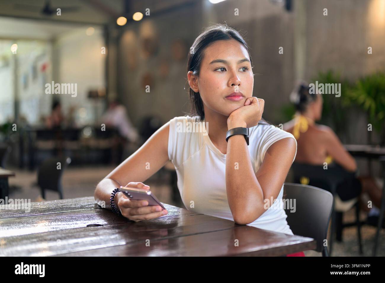 Glückliche Frau, die sich im Café entspannt, während sie ihr Handy hält Stockfoto