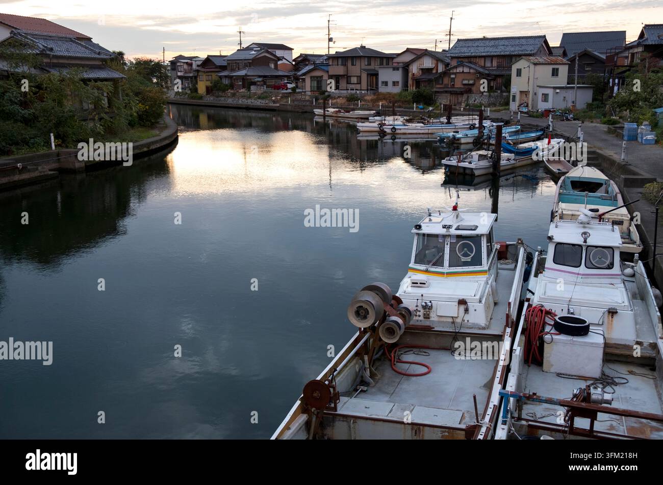 Kommerzielle japanische Fischerboote (Gyosen, 漁船) am Dock in einer Wohngegend an einem Wasserweg des Biwa-Sees (Biwako, 琵琶湖) in Hikone, Shiga, Japan. Stockfoto