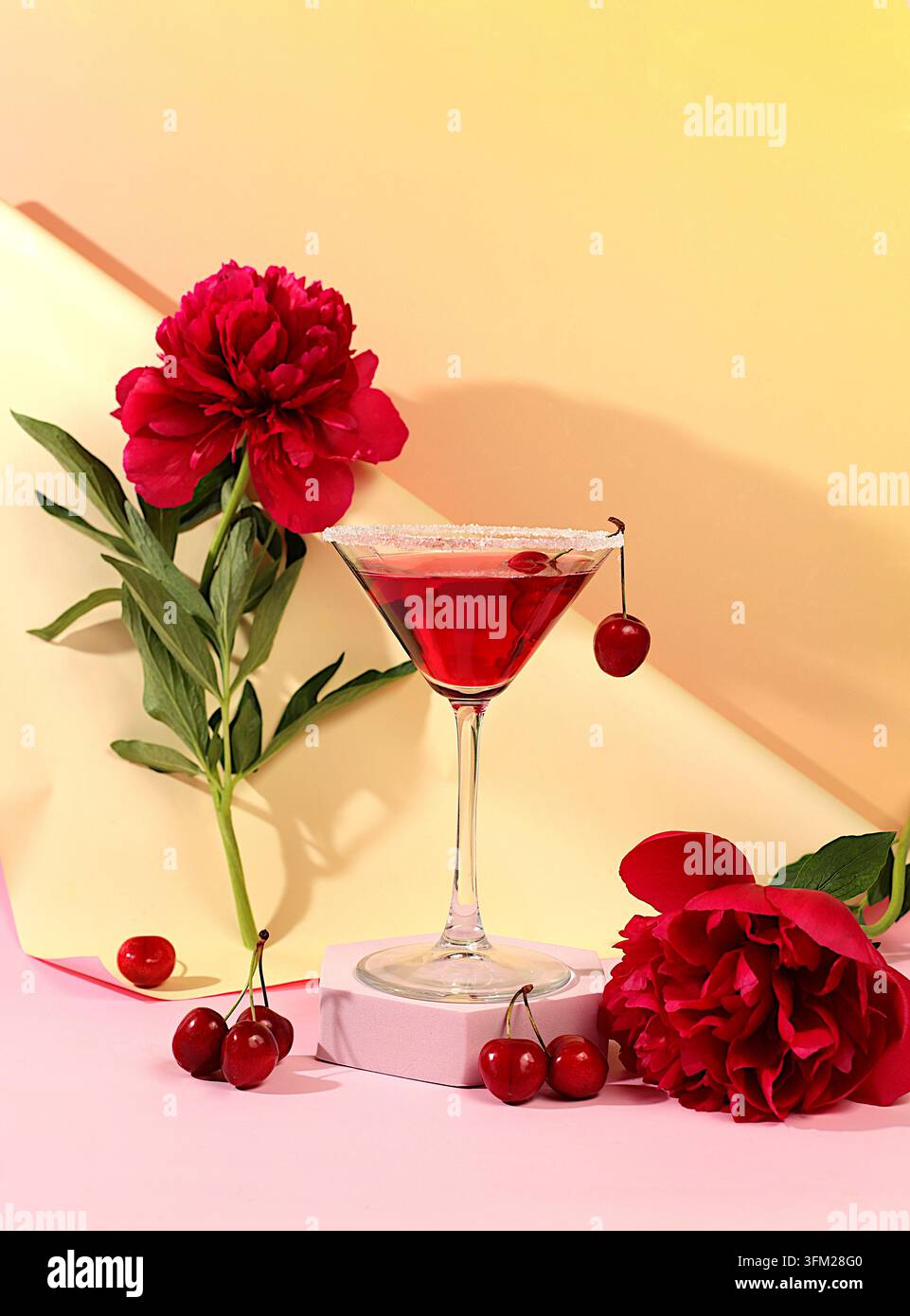 Moderne Stillleben mit einem sommerlichen alkoholischen Cocktail und Pfingstrosen vor sonnigem Hintergrund. Kirsch-Martini auf Eis für eine Party. Minimalistisches Konzept Stockfoto