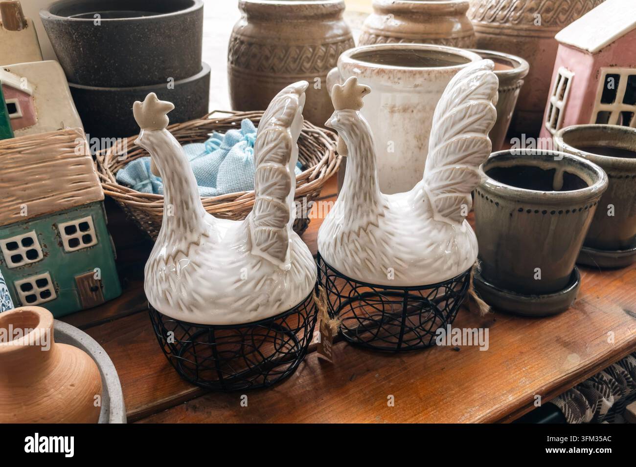 Keramik-Hahn-Figuren und Eieraufbewahrungskörbe im Gartenladen ausgestellt - Smartphone-aufgenommenes Stockfoto