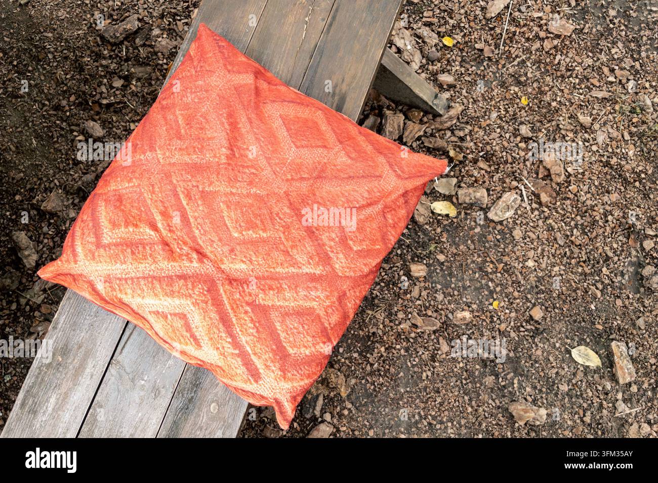 Terrakotta-musteriges Outdoor-Kissen auf Holzgartenbank platziert - Smartphone-aufgenommenes Stockfoto