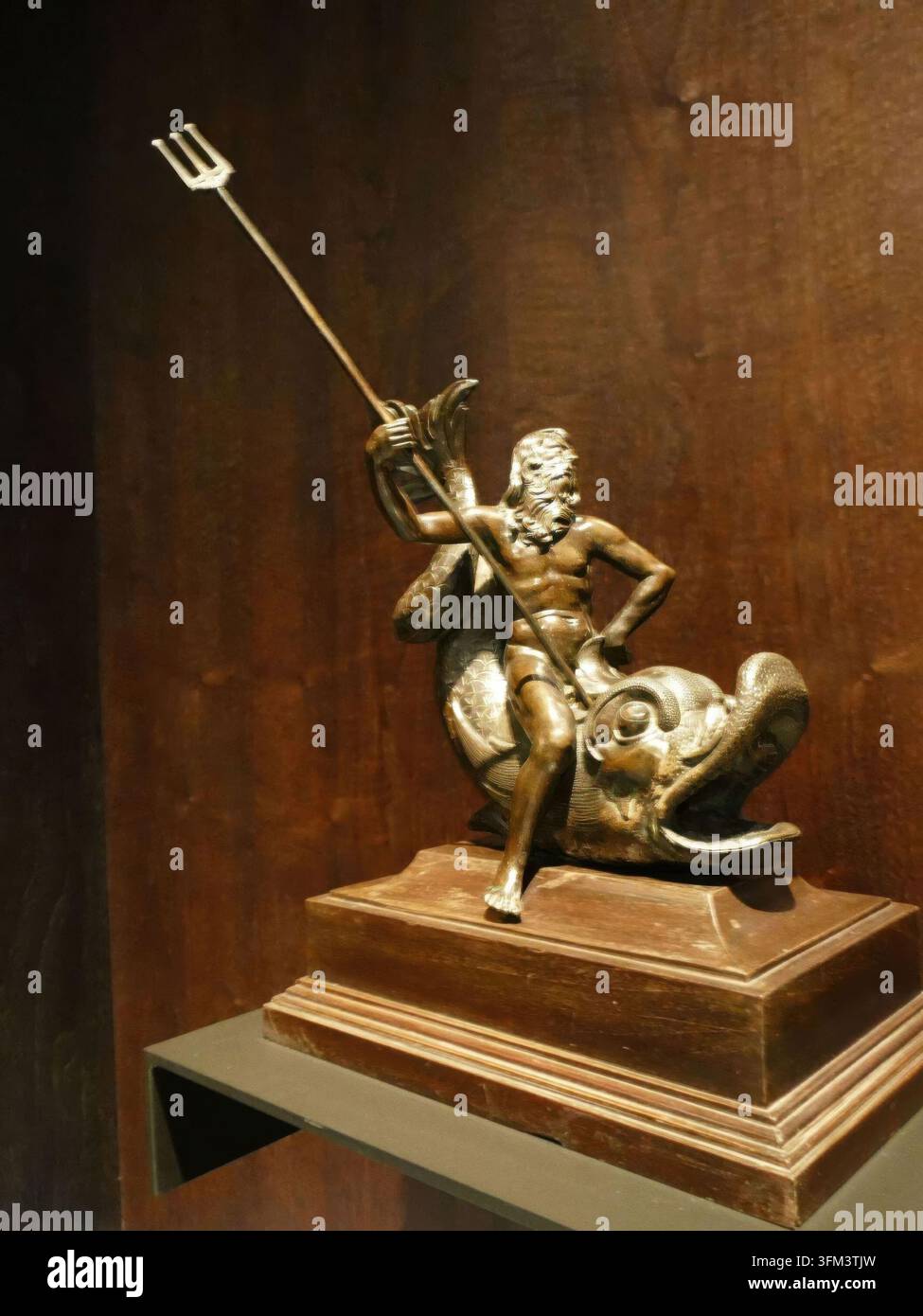 BUDAPEST - 26. NOV 2025 - Bronzene Neptun-/Poseidon-Skulptur, die einen Delphin reitet und einen langen Dreizack hält — klassische mythologische Meeresgott-Statue, Museum ex Stockfoto