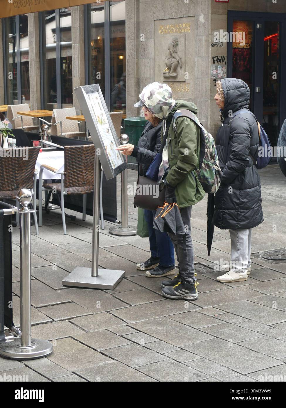 DÜSSELDORF, DEUTSCHLAND - 24. MAI 2025 - Touristen blättern in der Speisekarte eines Restaurants in der Nähe des Straßeneckens in bewölktem Köln, Deutschland Stockfoto
