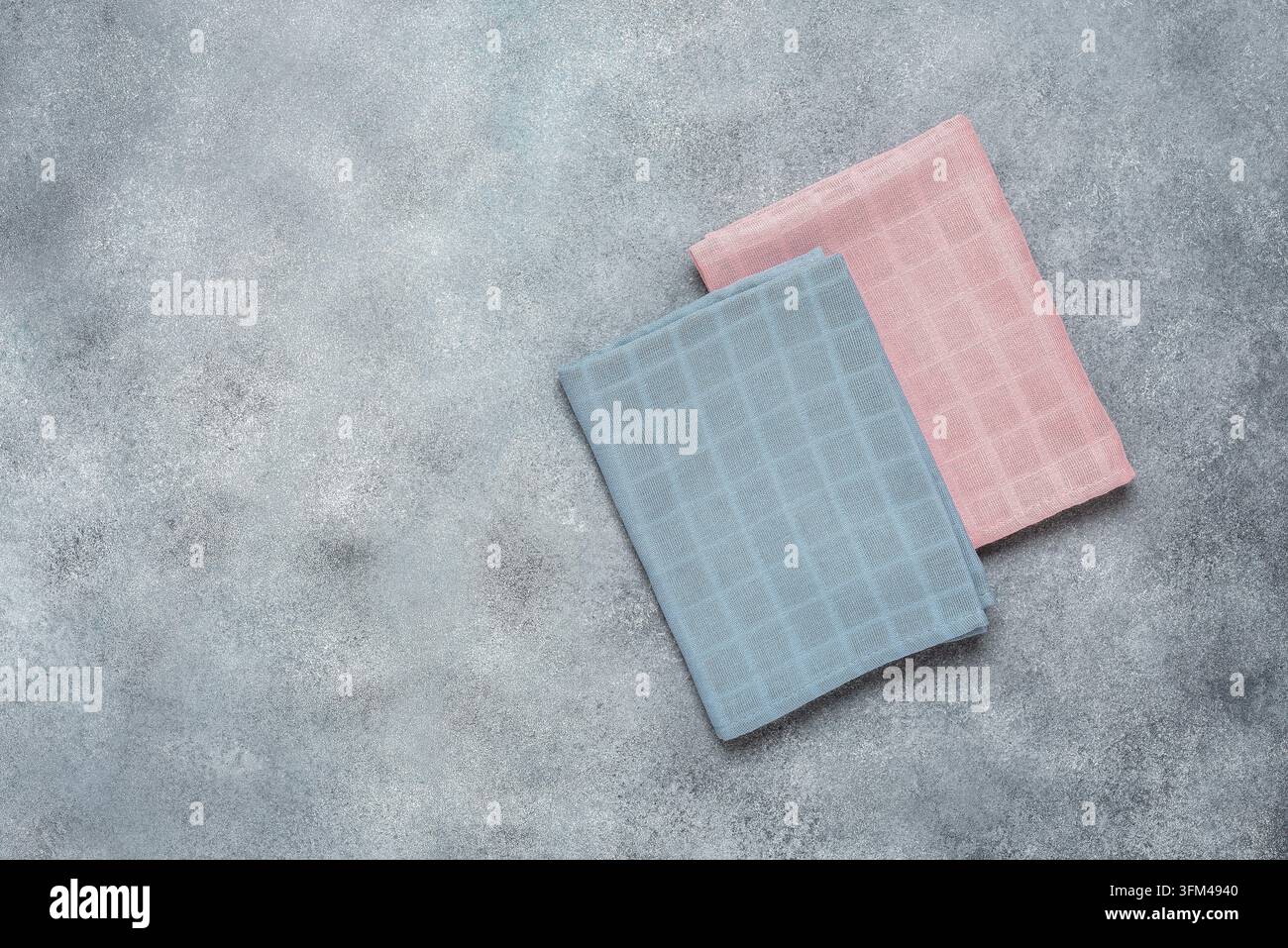 Pinke und blaue Baumwollservietten auf grauem Beton-Hintergrund. Draufsicht, flach liegend. Stockfoto