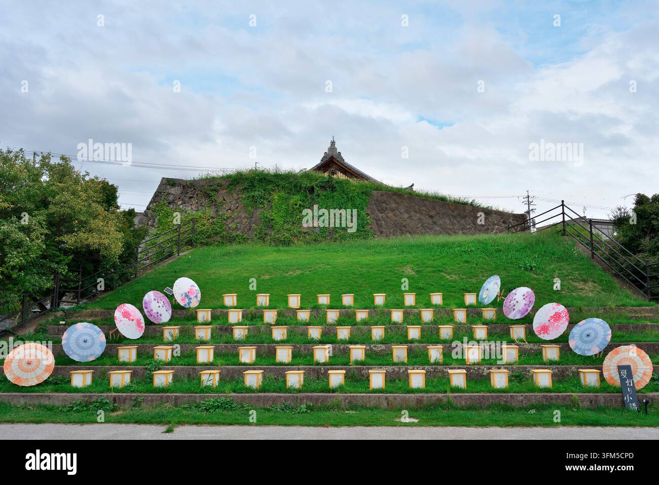 20. September 2025, Komoro, Japan: Traditionelle japanische Papierlaternen und farbenfrohe dekorative Regenschirme, die auf Steinstufen während eines saisonalen Events ausgestellt sind Stockfoto