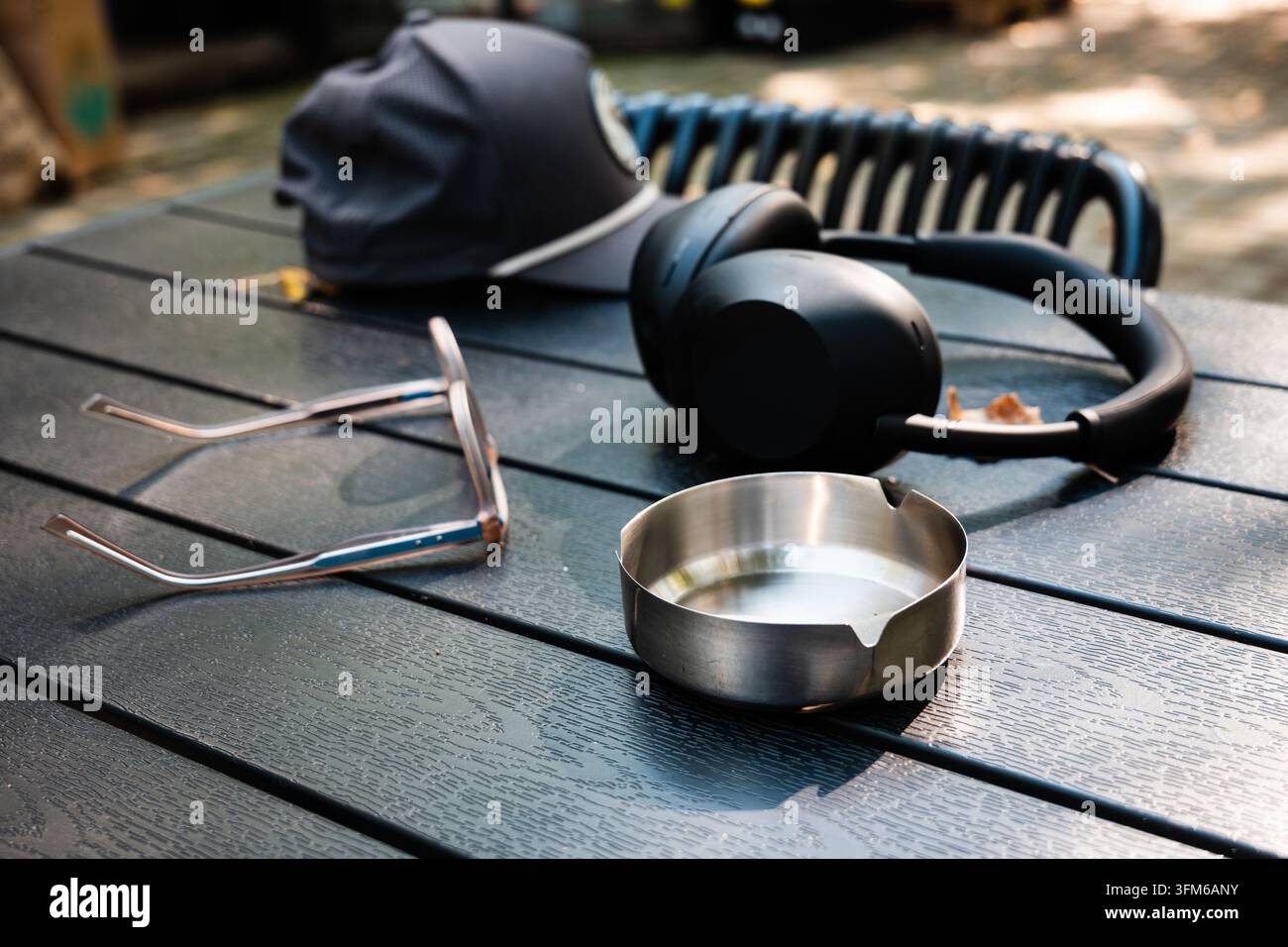 Persönliche Gegenstände für Freizeit und Entspannung im Freien, darunter Kopfhörer, ein Baseballcap, eine Sonnenbrille und ein Aschenbecher Stockfoto
