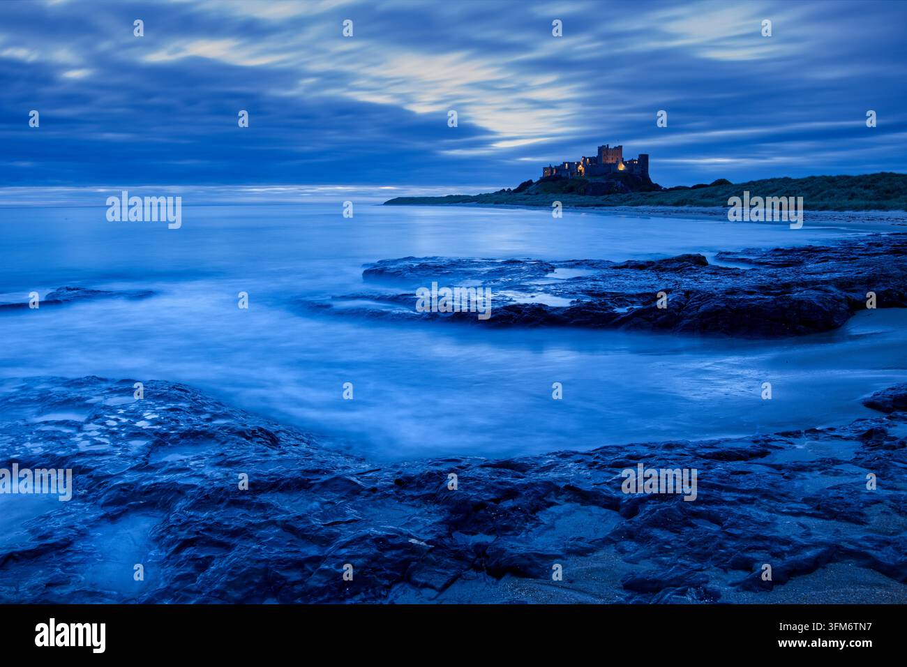 Bamburgh Castle in Northumberland vor Sonnenaufgang, gesehen von den Harkess Rocks Stockfoto