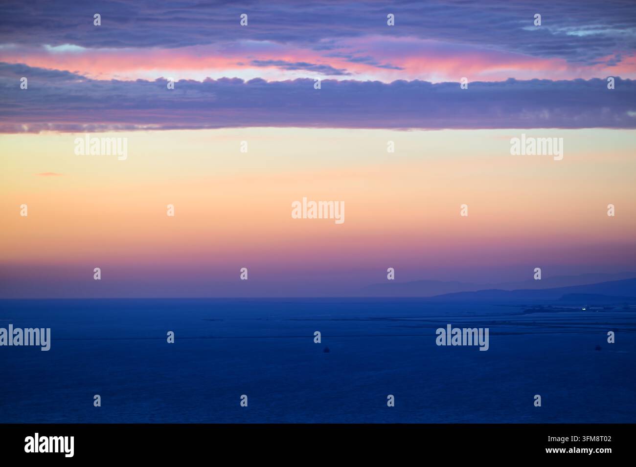 Sanftes pastellfarbenes Sonnenuntergang über ruhigem Ozean mit geschichteten Wolkenbändern und breitem horizontalem Farbverlauf, minimalistisches Seelandschaft für Hintergründe und Reise-Bilder Stockfoto