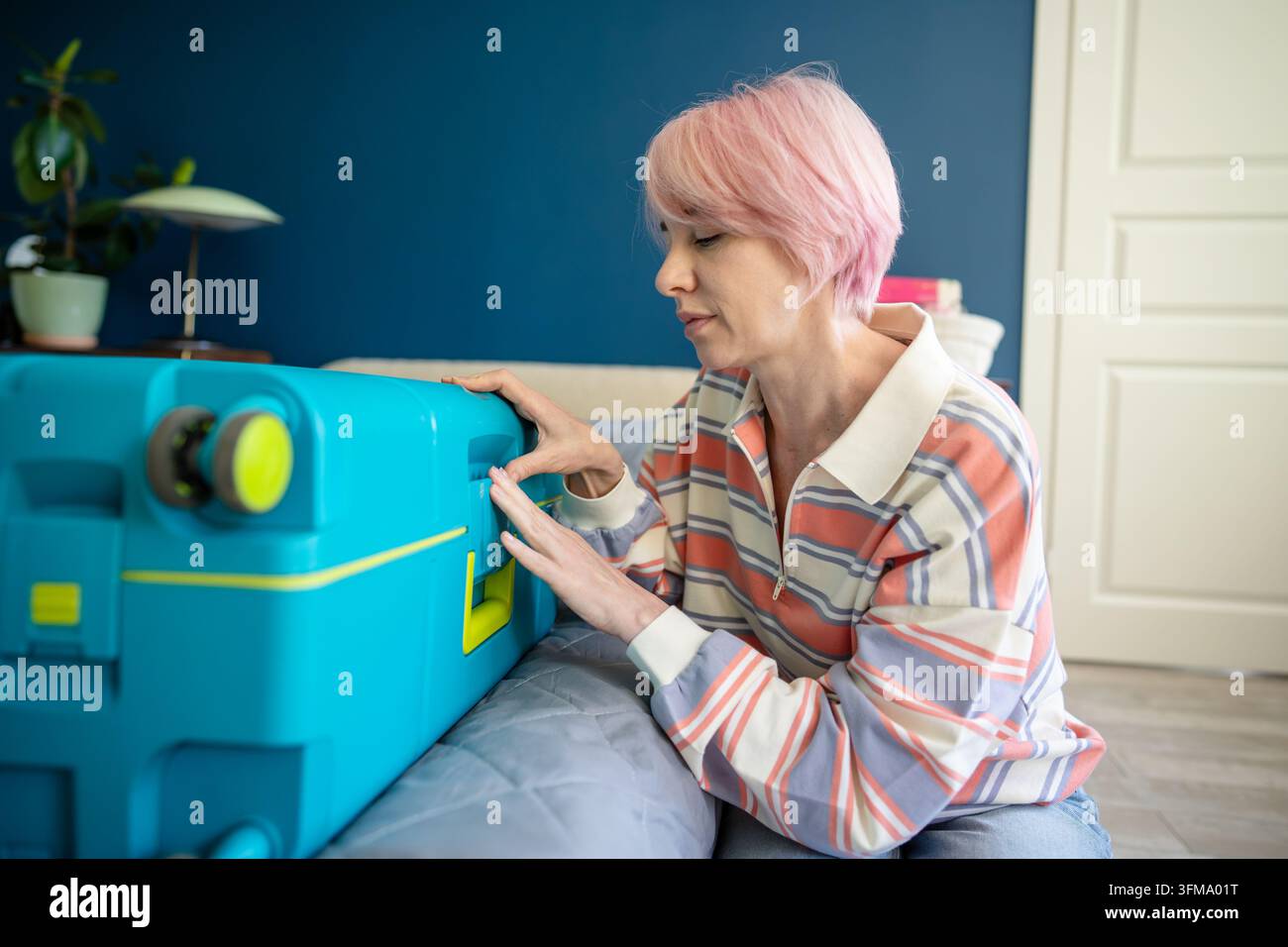 Entspannte Frau, Reisende, hat die Vorbereitungen ihres persönlichen Gepäcks abgeschlossen, bevor sie zu ihrer Urlaubsreise aufbricht. Stockfoto