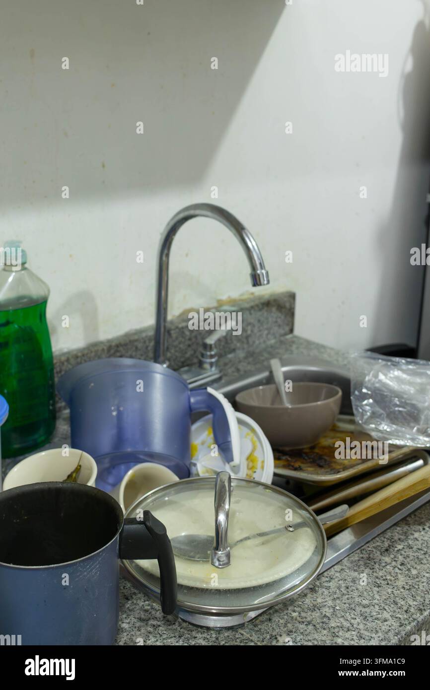 Schmutziges Geschirr und Besteck türmen sich in einem Küchenspülbecken und müssen gespült werden Stockfoto