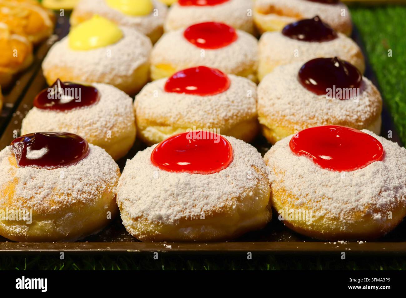 Puderzucker-Donuts mit Erdbeer-, Blaubeer- und Vanillecreme-Toppings auf einem Tablett an einem Straßendessertstand, Nachtmarkt, Thailand Stockfoto