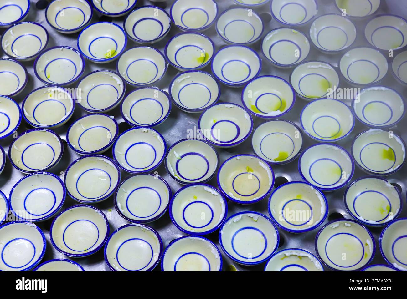 Leere keramische Khanom-Thuai-Schüsseln mit blauen Ringen in einem Edelstahl-Dampfgarer nach dem Entfernen der Desserts, mit aufsteigendem Dampf. Stockfoto