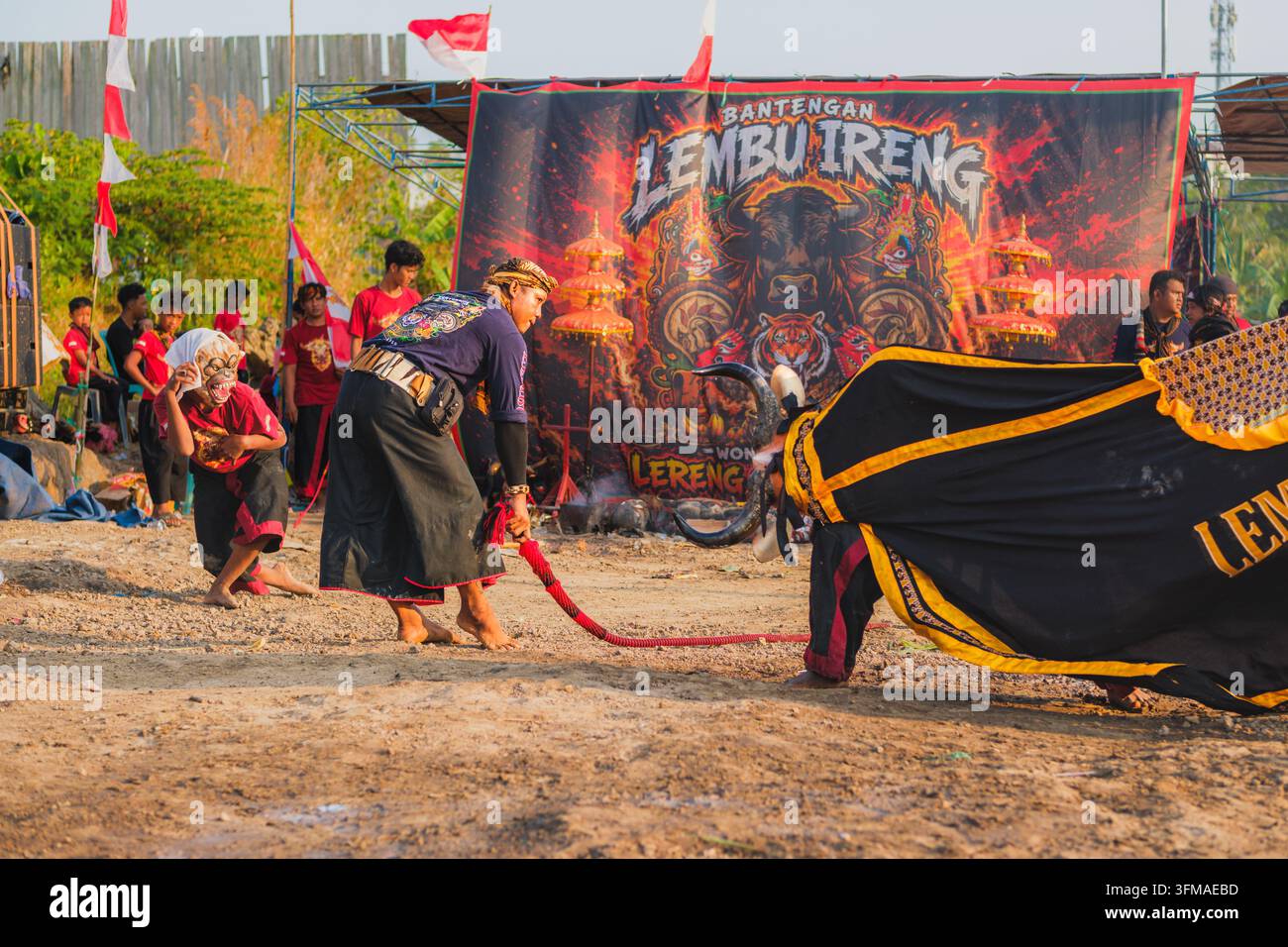 Balikpapan, Indonesien - 25. August 2026. Darsteller, der eine Peitsche schwingt, und ein Darsteller, der eine Affenmaske trägt, während eines traditionellen indonesischen Bantengan. Stockfoto