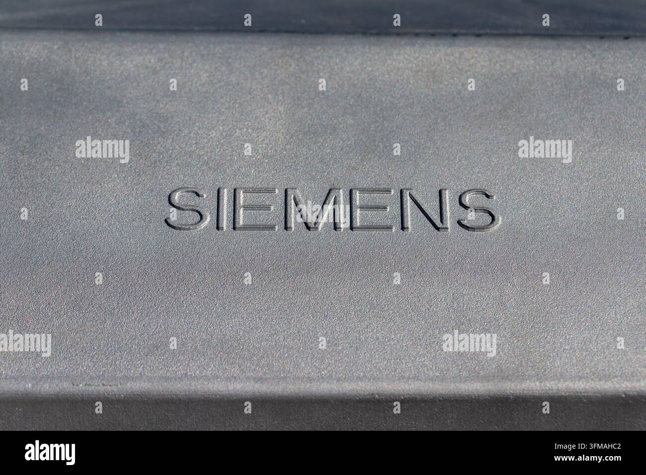 Siemens-Markennamenprägung auf einer dunkelgrauen Metalltextur, die Ingenieurwesen und Technologie repräsentiert Stockfoto