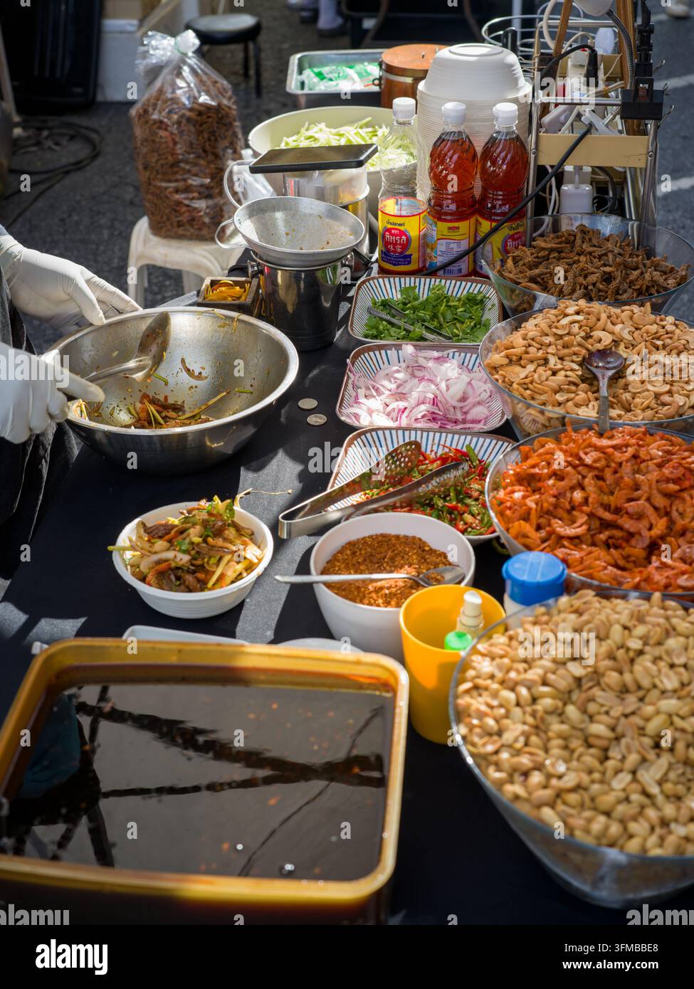 Thailändischer Straßenhändler bereitet ein Gericht mit getrockneten Garnelen, Cashewnüssen, Erdnüssen, Kräutern und Gewürzen an einem authentischen thailändischen Marktstand in Thailand zu. Stockfoto