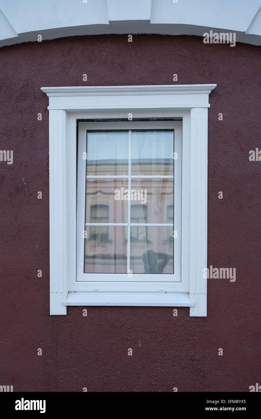 neutrales Fenster an einer gestrichenen Holzfassade mit rotbraunen Akzenten, Außenansicht geradeaus, gewerbliche Immobilienkulisse, weiß und rotbraun Stockfoto