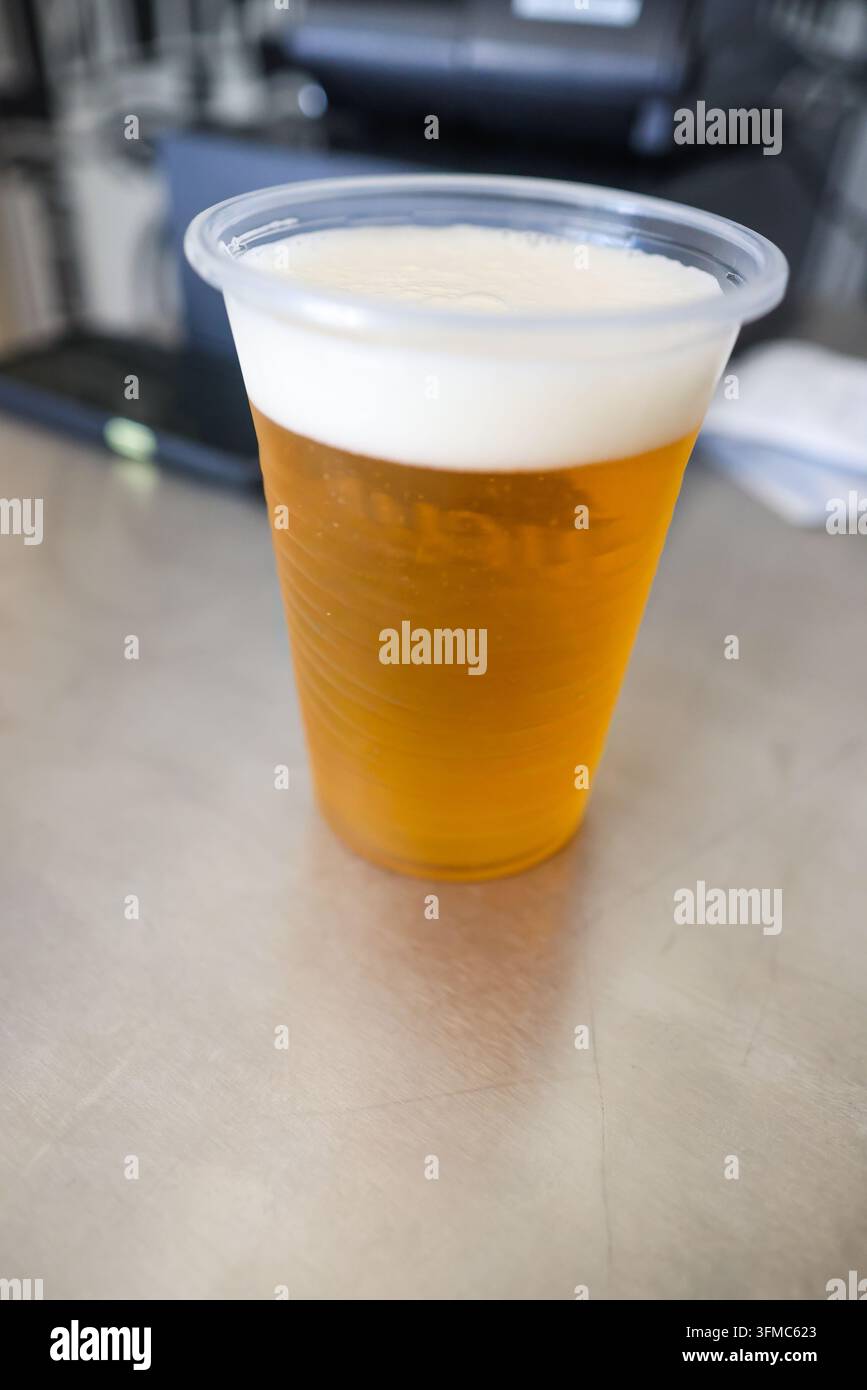 Ein kaltes goldenes Bier in einem klaren Plastikbecher. Stockfoto