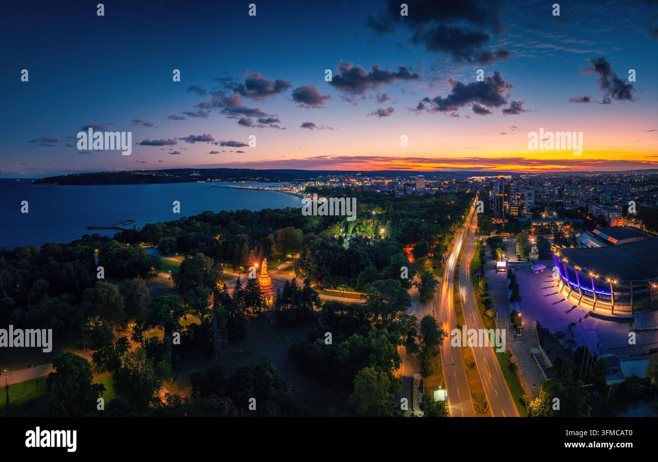Panoramischer Luftblick auf die Küste von Varna mit dem Palast der Kultur und des Sports, dem Meeresgarten und den Stadtlichtern in der Dämmerung Stockfoto