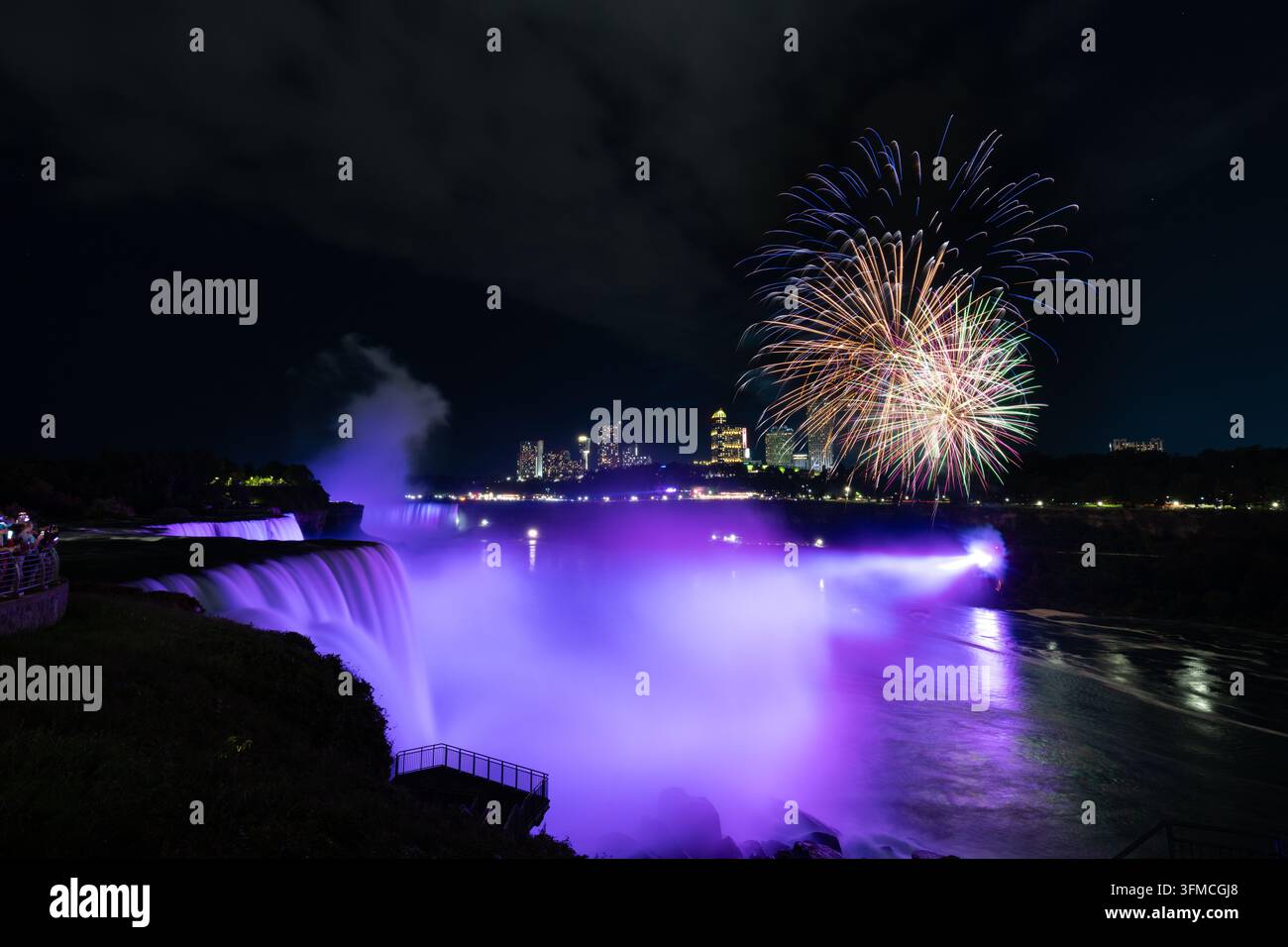 Feuerwerke, die über violett beleuchteten Niagarafällen in der Nacht explodieren Stockfoto