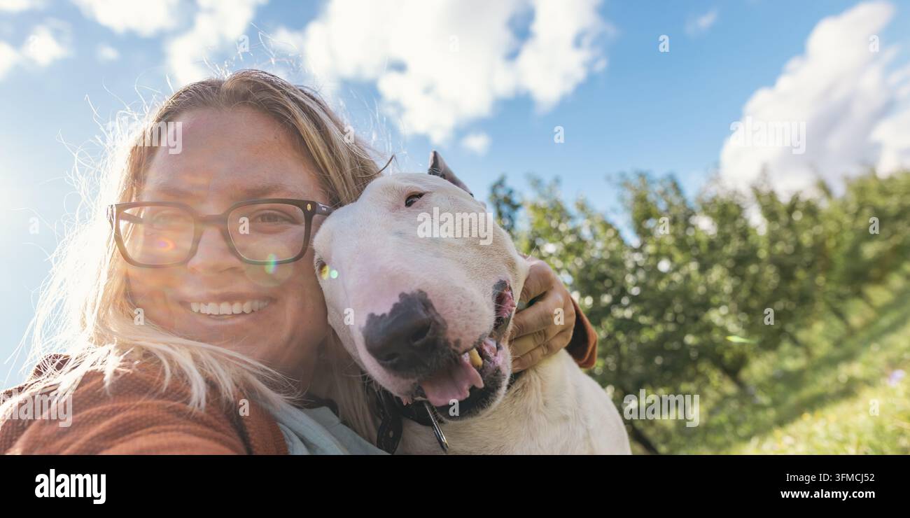 Zweijähriger Junge geht mit einem Hund in einem Apfelgarten Stockfoto
